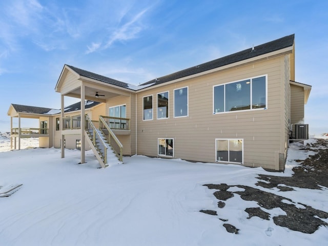 snow covered rear of property with central AC and ceiling fan