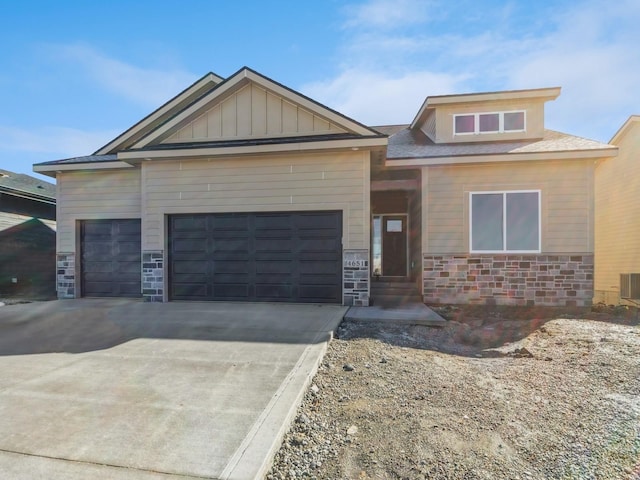 view of front facade featuring stone siding, a garage, driveway, and board and batten siding