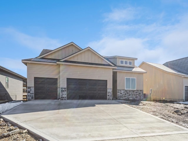 craftsman-style house with stone siding, board and batten siding, an attached garage, and driveway