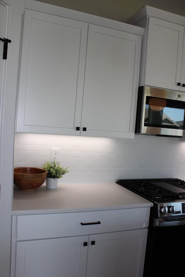 4651 180th St, Urbandale, IA 50323 - kitchen view of stainless steel appliances, decorative backsplash, white cabinets, and light countertops