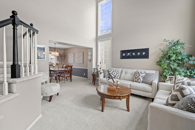 carpeted living room with a chandelier and a high ceiling