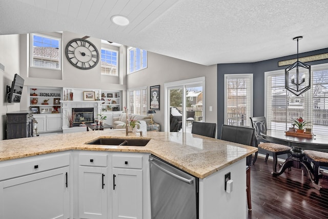 kitchen with a kitchen breakfast bar, light stone countertops, white cabinets, stainless steel dishwasher, and sink