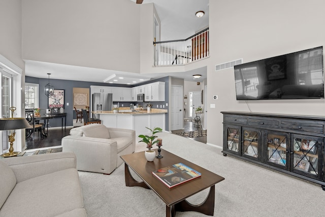 carpeted living room with a notable chandelier and a towering ceiling