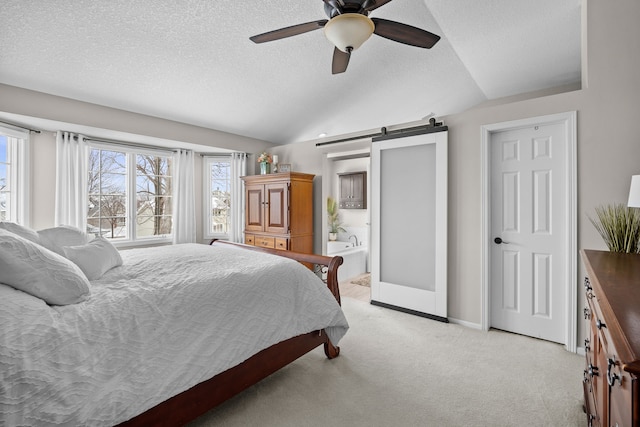 carpeted bedroom featuring vaulted ceiling, a textured ceiling, connected bathroom, ceiling fan, and a barn door