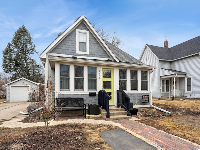 view of front of home featuring entry steps, a garage, an outdoor structure, driveway, and roof with shingles