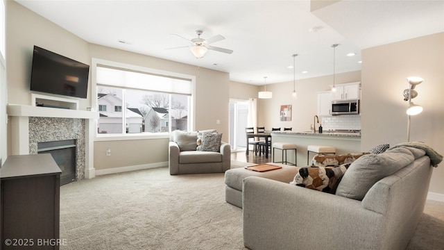 living room featuring light colored carpet, a fireplace, visible vents, and baseboards