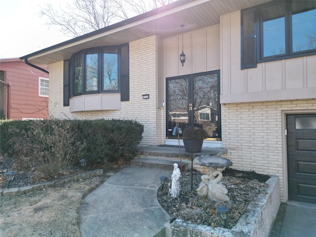 property entrance featuring board and batten siding and brick siding