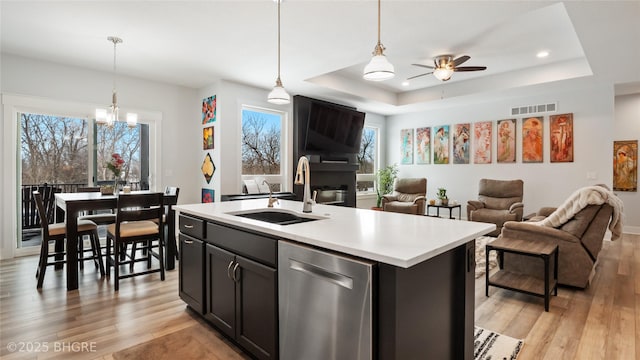 kitchen with light countertops, visible vents, a sink, an island with sink, and dishwasher