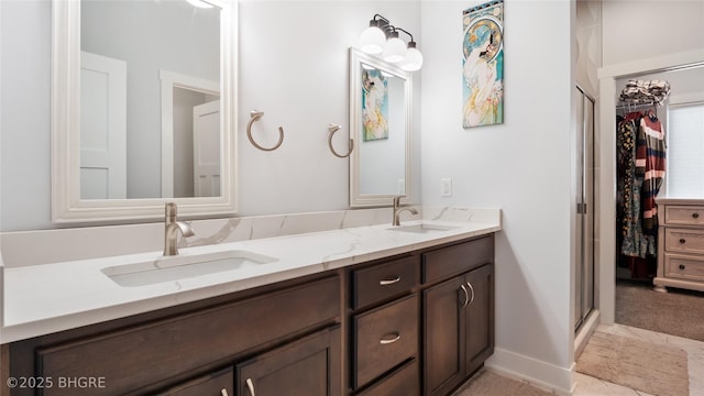 bathroom with double vanity, a shower stall, baseboards, and a sink