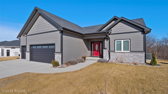 craftsman-style home with driveway, stone siding, an attached garage, central air condition unit, and a front lawn