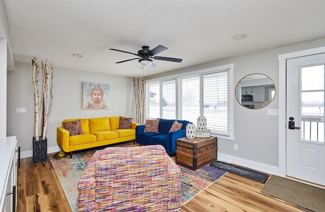 living room with hardwood / wood-style floors, plenty of natural light, ceiling fan, and a textured ceiling