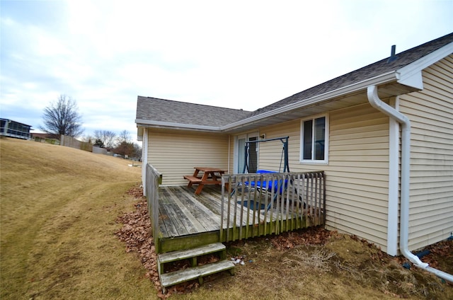 rear view of property with a shingled roof, a lawn, and a wooden deck