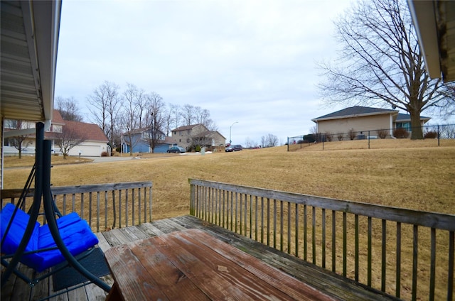 wooden deck with a residential view, fence, and a lawn