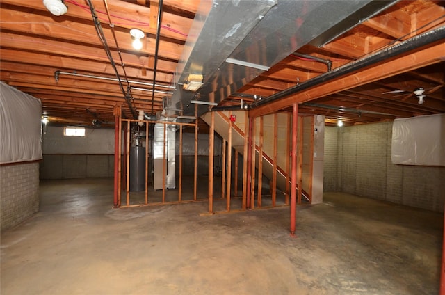 basement featuring water heater and brick wall