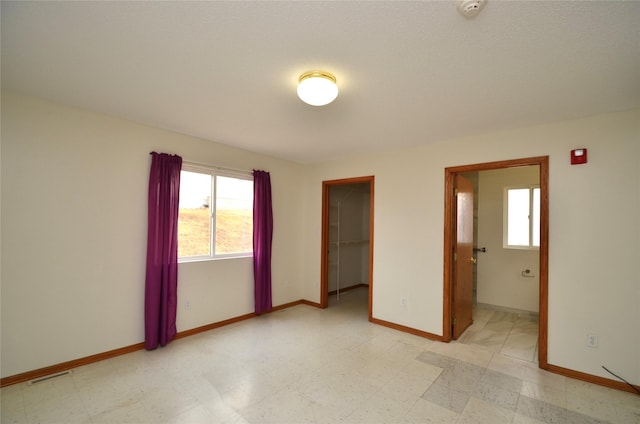 empty room featuring light floors, visible vents, and baseboards