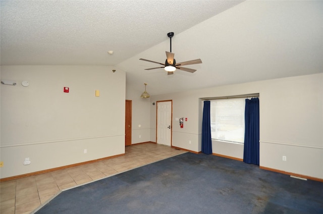 empty room featuring lofted ceiling, light carpet, ceiling fan, a textured ceiling, and light tile patterned flooring