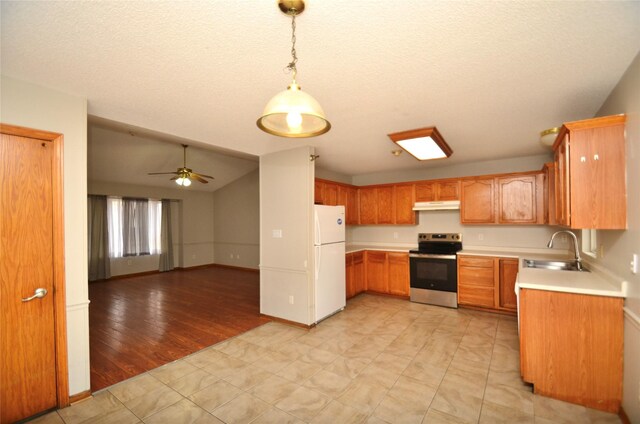 kitchen with a sink, hanging light fixtures, light countertops, stainless steel electric range, and freestanding refrigerator