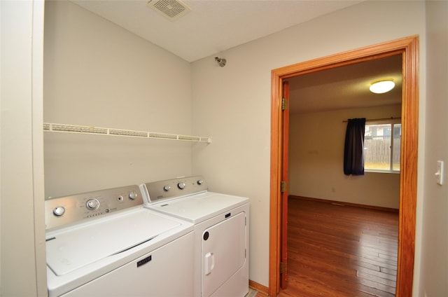 laundry room featuring laundry area, baseboards, visible vents, wood finished floors, and separate washer and dryer