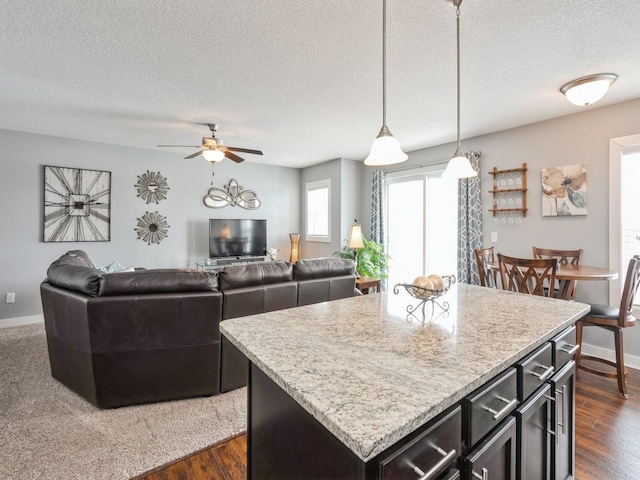 kitchen with hanging light fixtures, a center island, a textured ceiling, and dark hardwood / wood-style floors