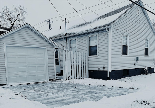 snow covered property featuring a garage and an outdoor structure