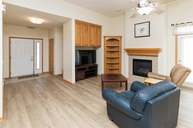 living room with ceiling fan, baseboards, light wood-style flooring, and a fireplace