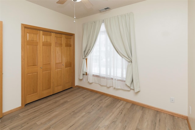 unfurnished bedroom featuring multiple windows, light hardwood / wood-style flooring, ceiling fan, and a closet