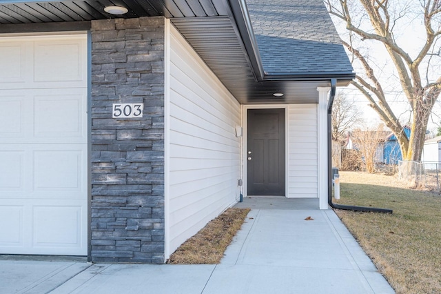 view of exterior entry featuring stone siding and roof with shingles