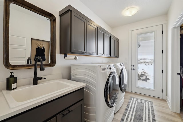 laundry room with light wood-style flooring, washer and clothes dryer, cabinet space, and a sink