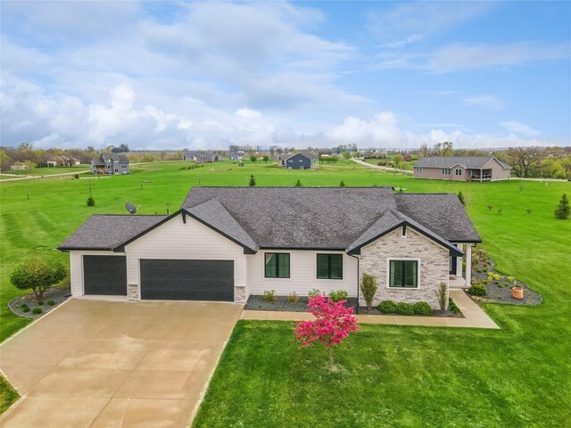 single story home with concrete driveway, a front yard, an attached garage, and stone siding
