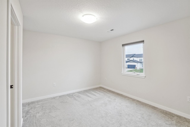 empty room featuring a textured ceiling and light carpet