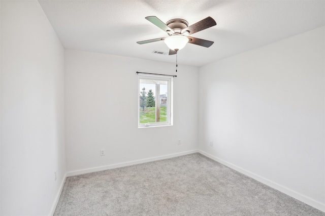 spare room with a textured ceiling, light colored carpet, and ceiling fan