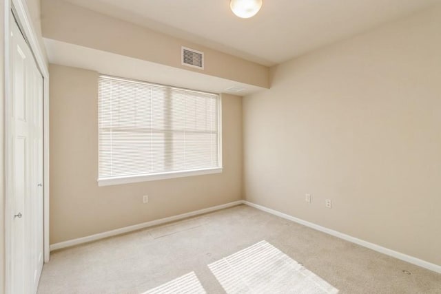 unfurnished bedroom featuring light carpet and a closet