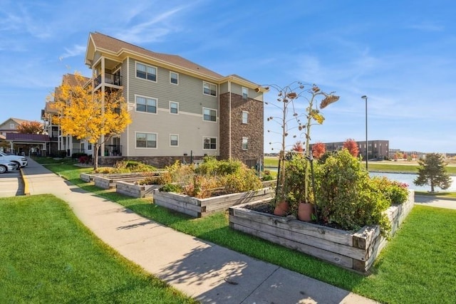 view of home's community with a water view and a lawn