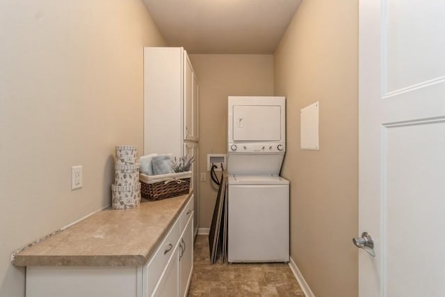 laundry room featuring cabinets and stacked washer / dryer