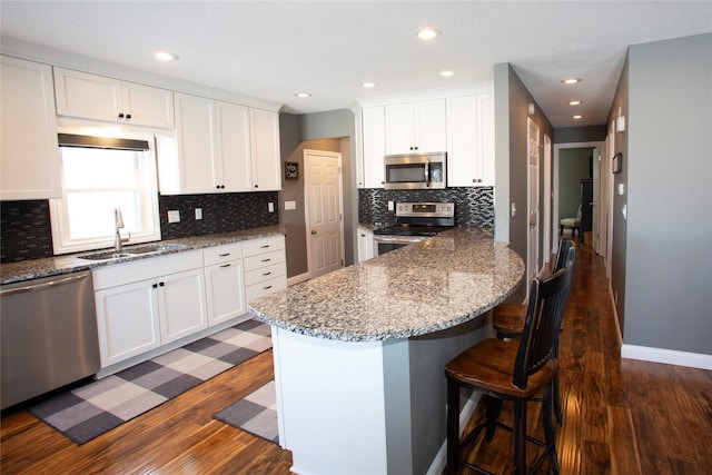 kitchen with sink, appliances with stainless steel finishes, white cabinets, and dark stone counters