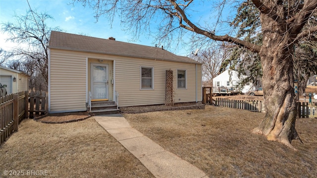 rear view of house featuring entry steps, a fenced backyard, and a yard