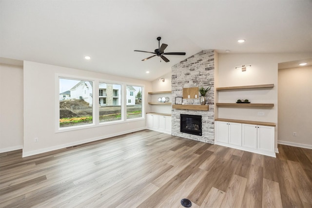 18258 Hidden Knl, Clive, IA 50325 - unfurnished living room with a ceiling fan, wood finished floors, vaulted ceiling, a stone fireplace, and baseboards