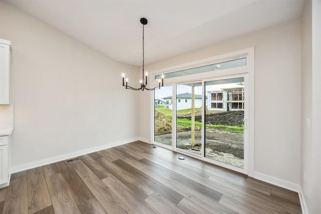 18258 Hidden Knl, Clive, IA 50325 - unfurnished dining area with a chandelier, wood finished floors, and baseboards