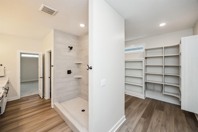 18258 Hidden Knl, Clive, IA 50325 - bathroom with a tile shower, wood finished floors, vanity, and recessed lighting