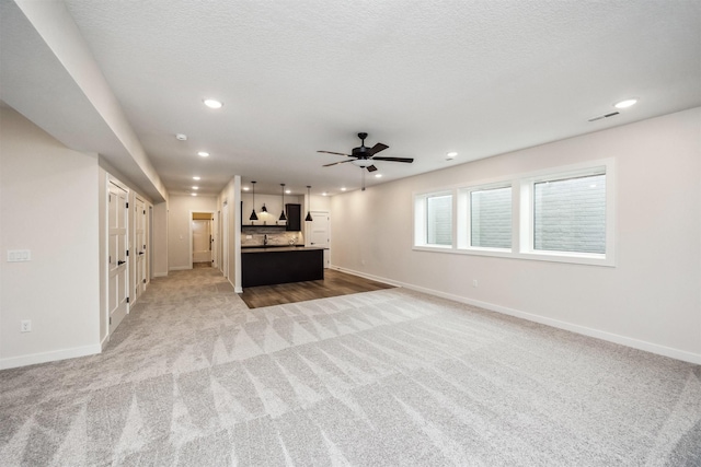 18258 Hidden Knl, Clive, IA 50325 - unfurnished living room with carpet floors, baseboards, recessed lighting, ceiling fan, and a textured ceiling
