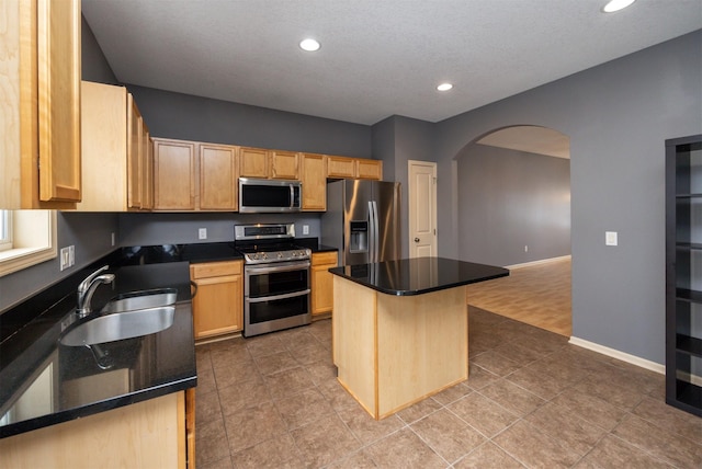 kitchen with sink, stainless steel appliances, a center island, and light brown cabinets