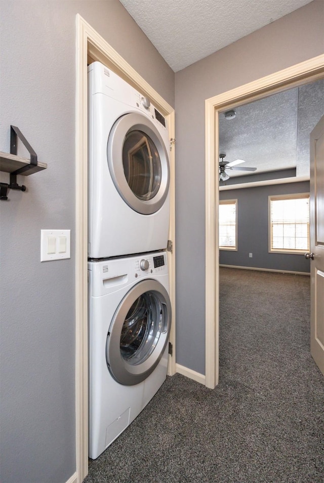 washroom featuring a textured ceiling, stacked washer / dryer, dark carpet, and ceiling fan