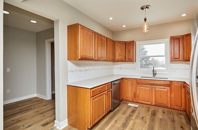 kitchen with sink, pendant lighting, light hardwood / wood-style floors, and backsplash