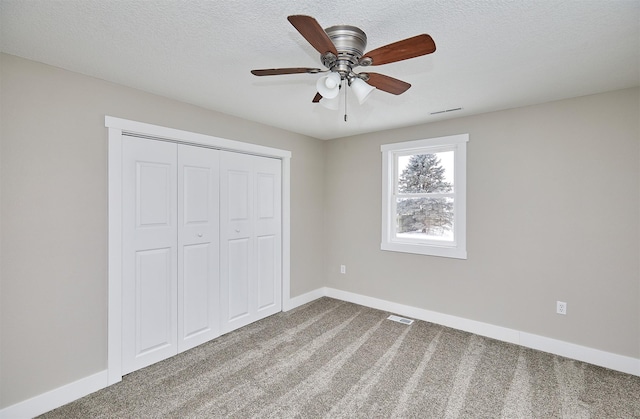 unfurnished bedroom featuring carpet, a closet, ceiling fan, and a textured ceiling