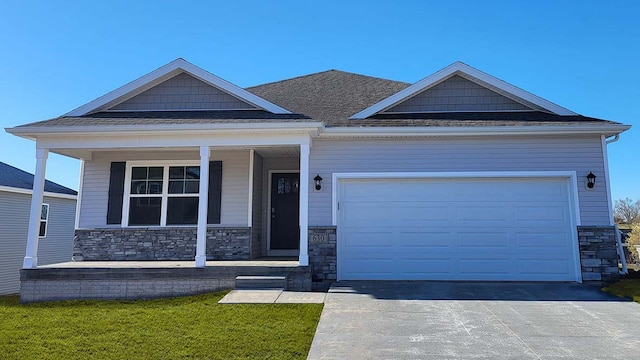 craftsman house with a garage, covered porch, and a front yard