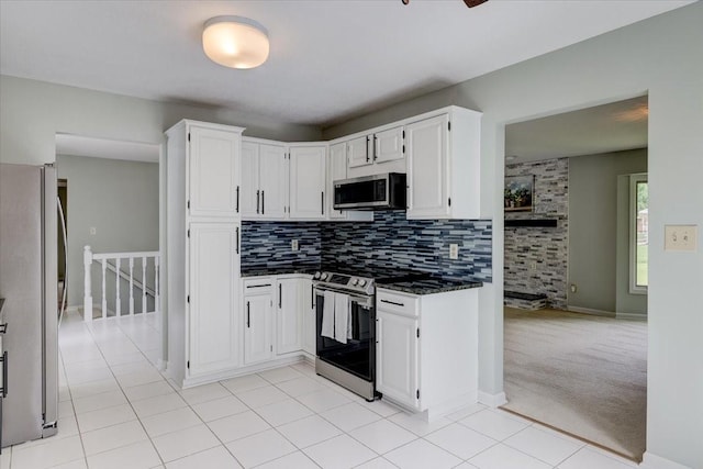 kitchen with appliances with stainless steel finishes, white cabinetry, light tile patterned floors, and decorative backsplash