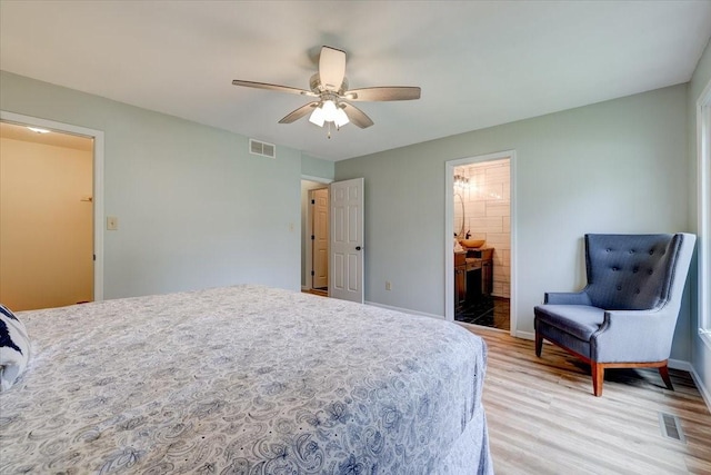 bedroom with ensuite bath, ceiling fan, and light hardwood / wood-style flooring