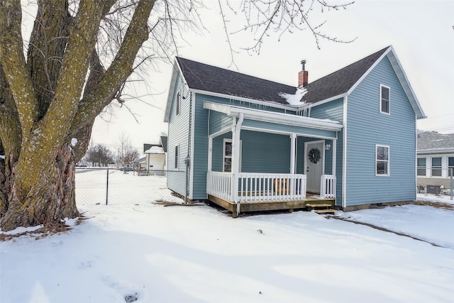 view of front of property with covered porch, a chimney, and fence