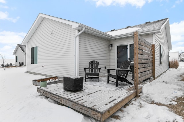 snow covered back of property with a deck