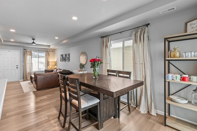 dining area featuring ceiling fan, light hardwood / wood-style floors, and a raised ceiling